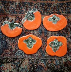 four orange ceramic pumpkins sitting on top of a rug