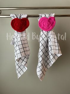 two red and white towels hanging from a towel rack on a clothes line with hearts attached to them