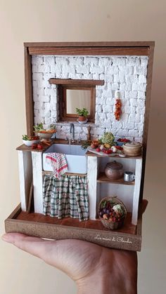 a hand holding a miniature model of a kitchen