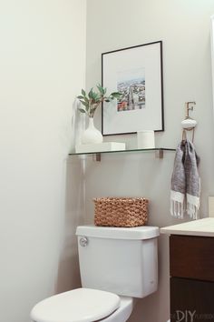 a white toilet sitting in a bathroom next to a wooden cabinet and shelf above it