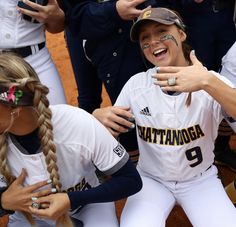 two softball players with their arms around each other in the middle of a huddle