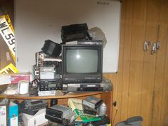 an old tv sitting on top of a wooden table next to other electronics and boxes