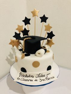 a graduation cake decorated with gold stars and a black hat