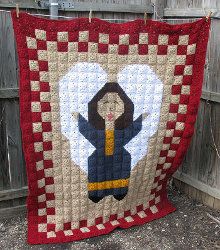 a red and white quilt with a woman holding a kite on it's back