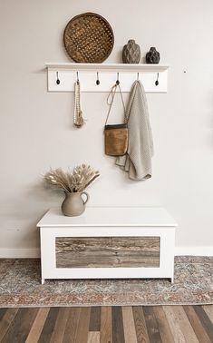 a white bench sitting under a wall mounted coat rack