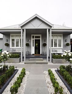 a gray house with white shutters and plants