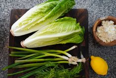 lettuce and other vegetables on a cutting board next to a bowl of rice