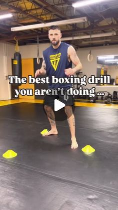 a man standing on top of a black mat in a gym holding a yellow frisbee