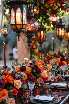 a long table is set with candles and flowers in vases, plates and place settings