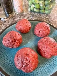 four red meatballs sitting on top of a blue plate