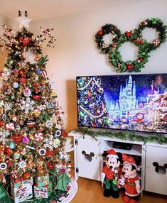 the christmas tree is decorated with mickey mouse ornaments and other holiday decorations in front of a television