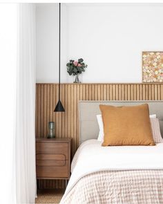 a bed sitting in a bedroom next to a wooden headboard and window with white drapes