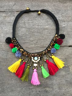 "This wax-cotton macrame braided necklace is covered in tigers eye crystals, brass and brightly colored tassels. The festive necklace is braided with beads and stones using wax string and made by Hmong Hill Tribe artisans in Northern Thailand. The necklace is 17\" long with two size loops and brass bead closure. The main design measures 5\" high and 4\" wide." Bohemian Braided Necklace As Gift, Bohemian Braided Jewelry For Festivals, Adjustable Braided Bohemian Necklace, Multicolor Amulet Necklace For Festivals, Bohemian Braided Necklace Gift, Braided With Beads, Hippie Braided Jewelry For Festival, Bohemian Multicolor Tassel Necklace For Festivals, Multicolor Beaded Amulet Necklace For Festivals