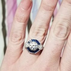 a woman's hand with a diamond and blue sapphire ring on top of it