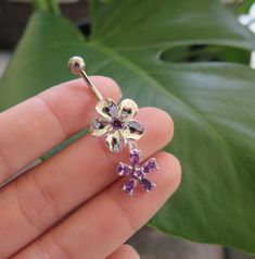 a person holding a flower shaped piercing with purple stones