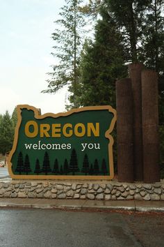 a welcome sign to oregon with trees in the background