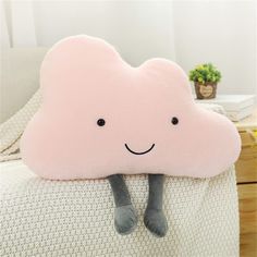 a pink cloud pillow sitting on top of a white couch next to a potted plant