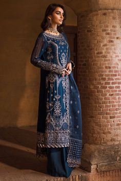 Elegant Royal Blue Embroidered Chiffon Pakistani Salwar Kameez ensemble that whispers tales of hidden depths and ancient mysteries. Crafted with the finest sequin embroidery on chiffon. Blue Embroidered Kameez: The main fabric of the Salwar Kameez is a vibrant shade of Blue The delicate floral organza border on the sleeves and hem evokes the fragrant blooms of a secret garden, while the raw silk bottoms lend a regal air of sophistication. Kameez Trouser: The kameez is paired with trousers to create a lavish Pakistani Party Dress. The fabric of these trousers is premium raw silk and it has a huge flare. Dupatta: A coordinating or contrasting dupatta would typically accompany the Salwar Kameez, serving as a versatile accessory. The dupatta may be adorned with complementary embroidery, border Dark Blue Shalwar Kameez, Embroidery On Chiffon, Embroidery Border, Pakistani Salwar, Salwar Kameez Online, Pakistani Salwar Kameez, Silk Bottoms, Embroidered Chiffon, Sequin Embroidery