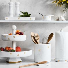 three tiered trays with utensils and fruit in them on a marble countertop