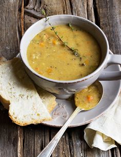 a bowl of soup on a plate next to two pieces of bread