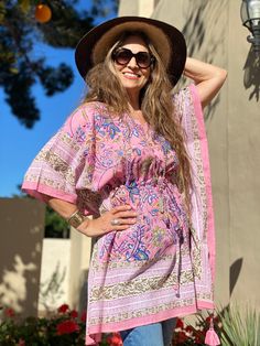 Our Rosa Tropicale short kaftan dress or top will transport you and everyone around you to the tropics with just one look! The pink ground colour of this print reminds us of the English cabbage roses that grow in Jean Marie's garden on the beautiful Isle of Wight in the UK. Hence the name ROSA, however with a TROPICALE twist. This intricate botanical hand block print is certain to make you smile wherever you wear it or take it! It works beautifully over white capri pants or shorts! Length 32" On Pink Printed Summer Beach Dress, Pink Printed Beach Dress For Summer, Pink V-neck Kaftan For Summer, Spring Pink Printed Beach Dress, Pink Printed Beach Dress For Spring, Pink Summer Kaftan For Beach Cover-up, Pink Flowy Tropical Dress, Flowy Tropical Pink Dress, Flowy Pink Tropical Dress