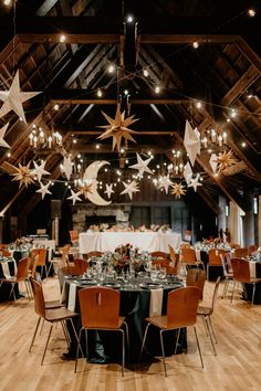 the tables are set for an event with stars hanging from the ceiling and lights above them