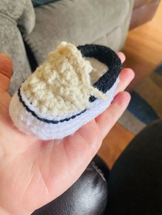 a hand holding a small crocheted slipper in the palm of someone's hand