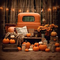 an old truck with pumpkins and candles on the bed in front of it is surrounded by fall decorations