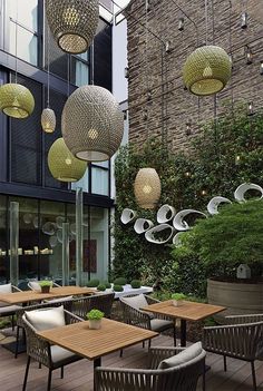 an outdoor dining area with tables and chairs, hanging lights and potted planters