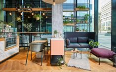 a living room filled with furniture and lots of windows next to a wooden floor covered in potted plants