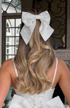 the back of a woman's head wearing a white dress with a large bow