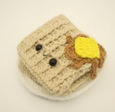 a small crocheted object with a face on it's side sitting on a white surface