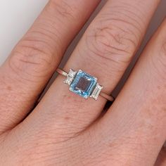 This beautiful ring features a 1.08 carat emerald cut aquamarine gemstone with natural earth mined baguette diamond accents, all set in solid 14K gold. This ring makes a lovely March birthstone gift for your loved ones! This ring is made with solid 14K Gold and natural Earth mined SI / G-H diamonds. As listed, this ring is ready to ship. If you're interested in purchasing this setting with a different center stone please message us! Emerald-cut Topaz Ring In 14k White Gold, Blue Topaz Baguette Cut Ring, Baguette Cut Blue Topaz Ring, Designer Silver Jewellery, Jewelry Showcases, Aquamarine Ring, March Birthstone, Birthstone Gifts, Aquamarine Rings