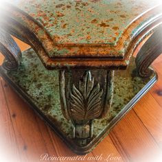 an old, rusty metal box with a leaf design on the lid sits on a wooden floor