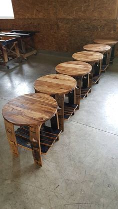 several tables made out of wooden pallets in a room with concrete floors and walls