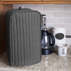 an oven mitt sitting on top of a counter next to cups and coffee mugs