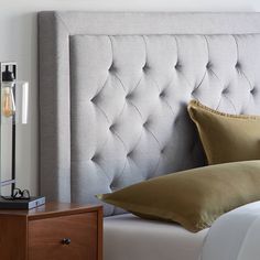 an upholstered headboard in a bedroom with pillows on the bed and nightstand