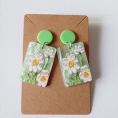 a pair of green and white earrings with flowers painted on them