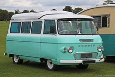 an old blue and white van parked next to a camper trailer in a field