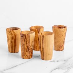 four wooden cups sitting on top of a white counter