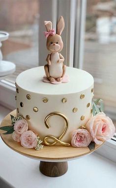 a white cake with pink flowers and a bunny on top