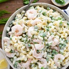 a bowl full of pasta salad with peas and shrimp