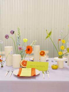 a table topped with lots of white vases filled with different types of flowers and fruit