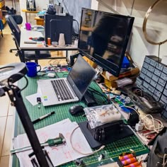 a messy desk with two laptops and many other items on it, including wires