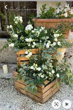 two wooden boxes filled with white flowers and greenery