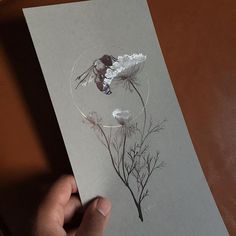 a person holding up a piece of paper with flowers on it