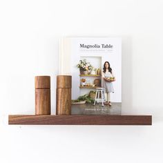 a book is sitting on top of a shelf next to two wooden pegs and a potted plant