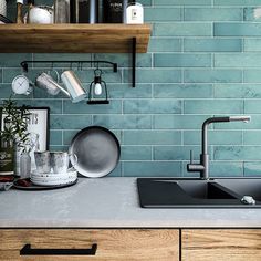 a kitchen with blue tiles and wooden shelves on the wall, including a black sink