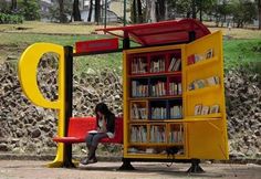 a woman sitting on a bench in front of a yellow book case with bookshelves