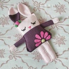 a crocheted stuffed animal laying on top of a bed covered in pink and purple flowers